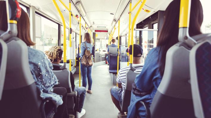 Passengers seated inside a city bus with yellow poles