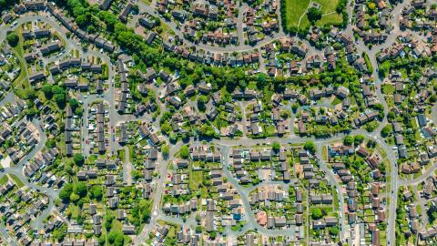 Aerial view of a suburban neighborhood with houses, roads, and green spaces