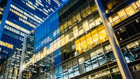 Glass office building with illuminated windows at night.